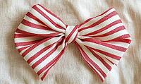 Simple red and white striped ribbon bow on a beige linen background. AI generated [IBR125000272]