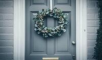 Simple holiday wreath made of pine branches and small white berries, hanging on a light gray wall. AI generated [IBR125000288]