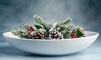 White ceramic bowl filled with snowy pinecones and a small sprig of holly, set against a muted blue-gray background. AI generated [IBR125000295]