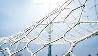 White nylon goal net filling entire frame edge to edge caught mid-violent-vibration with diamond mesh pattern distorted and stretched in multiple directions simultaneously, sharp at centre and motion-blurred at edges showing physical resonance from powerf [IBR125000330]