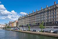Classicist residential buildings on Quai Fulchiron stretch along the quay wall of the Saone River in the historic Vieux Lyon district under blue summer skies in Lyon, Vieux Lyon, Metropole de Lyon, Rhone, Auvergne-Rhone-Alpes, France [IBR125002336]