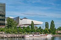 The deconstructivist architecture of the Musée des Confluences, designed by the Viennese architectural firm Coop Himmelb (l) au, on the banks of the Saône at Quai Rambaud, with a traditional péniche moored by the river against a backdrop of green trees, s [IBR125002342]