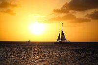 Sunset sailing scene over the ocean, featuring a catamaran and a smaller boat in the distance. Aruba vacation landscape [IBR125026132]