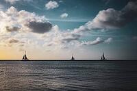 Three sailboats on a calm sea with a dramatic sky filled with clouds during sunset. Aruba, The Netherlands [IBR125026134]