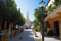 Greek Orthodox Evangelistria church in an alley with colorful chairs, flowers and trees, Paleochora, Kandanos-Selino municipality, Chania Regional Unit, Crete, Greece [IBR125026191]