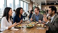Four professionals of diverse ethnicities and genders share smiles and conversation while dining on fresh salads and sandwiches in a bright, contemporary workspace cafeteria, AI generated [IBR125026367]