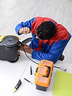Man repairman repairing vacuum cleaner at service center [IBR125062164]