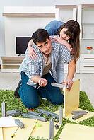 Young family assembling furniture at new house [IBR125062170]