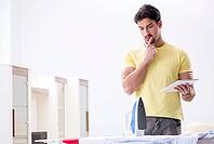 Handsome man husband doing clothing ironing at home [IBR125062185]