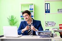 Businessman unhappy with excessive work sitting in the office [IBR125062190]