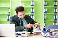 Businessman angry with excessive work sitting in the office [IBR125062191]