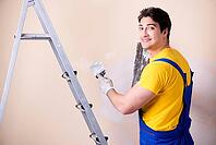 Young contractor employee applying plaster on wall [IBR125062249]