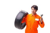 Young garage worker with tyre isolated on white [IBR125075746]