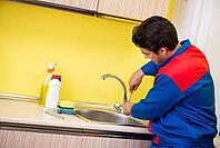 Plumber repairing tap at kitchen [IBR125075750]