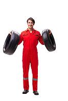 Young garage worker with tyre isolated on white [IBR125075777]
