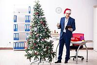 Young employee celebrating christmas at workplace [IBR125075800]