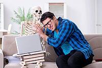 Student studying with skeleton preparing for exams [IBR125094381]