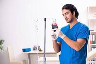 Young male doctor in blood transfusion concept [IBR125117993]