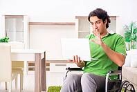 Young handsome man in wheelchair at home [IBR125117997]