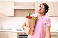 Young handsome man with vegetables in the kitchen [IBR125117999]