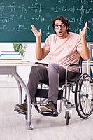 Young handsome man in wheelchair in front of chalkboard [IBR125118002]