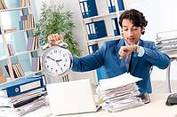 Young handsome male employee with too much work in the office [IBR125118021]