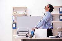 Young handsome male employee doing exercises in the office [IBR125118022]