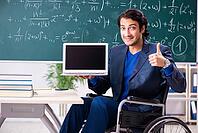 Young handsome man in wheelchair in front of chalkboard [IBR125118026]
