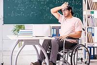 Young handsome man in wheelchair in front of chalkboard [IBR125118036]