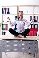 Young female employee doing exercises in the office [IBR125141676]
