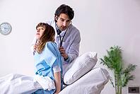 Male doctor visiting female patient in ward [IBR125141677]