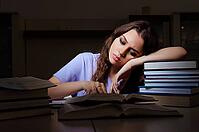 Young female student preparing for exams late at home [IBR125141700]