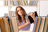 Young female student preparing for exams at library [IBR125141702]