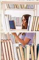Young female student preparing for exams at library [IBR125141706]
