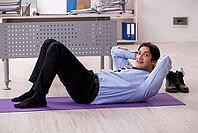 Young handsome male employee doing exercises in the office [IBR125141720]