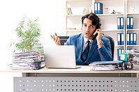 Young handsome busy employee sitting in office [IBR125141730]