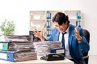 Young handsome busy employee sitting in office [IBR125141731]