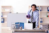 Young handsome male employee doing exercises in the office [IBR125141755]