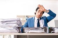 Young handsome busy employee sitting in office [IBR125141756]