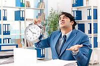 Young handsome male employee with too much work in the office [IBR125141760]