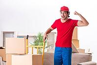 Young male contractor with boxes working indoors [IBR125141761]