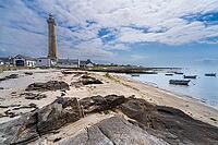 The Phare d'Eckmühl rises above Pointe de Saint-Pierre in Penmarc'h, Finistère, Brittany, France. Its tall stone tower and lantern dominate the low Atlantic coastal landscape, with surrounding lighthouse buildings, rocky ground and open sky visible in cle [IBR125163357]