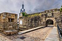 The old town and fortified Ville Close of Concarneau occupy a walled island in the Bay of Concarneau, Finistère, Brittany, France. Stone ramparts, towers, harbour buildings and surrounding water are visible in natural daylight, with the town opening towar [IBR125163362]