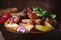 Ojakhuri, fried meat with potatoes, in ketsi, on a wooden table, Georgian cuisine, against a background of fresh ingredients [IBR125163378]