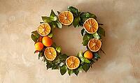 Small wreath of dried orange slices and green leaves, hanging on a beige wall. AI generated [IBR125167395]