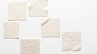 Five undyed pale fabric swatches in pentagon arrangement, different weave structures including cotton plain weave, polyester satin, wool boucle, nylon ripstop, rayon jersey, textile fiber identification reference material concept, white background, studio [IBR125167437]