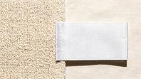 White woven garment care label lying on blended ivory fabric, raking light revealing two distinct thread types in fabric weave below, textile fiber mislabeling and authenticity concept, studio shot, AI generated [IBR125167439]