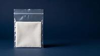 Clear sealed laboratory polyethylene bag containing plain unidentified white fabric swatch, fiber composition deliberately undisclosed, textile reference material blind validation test concept, deep navy background, studio shot, AI generated [IBR125167444]