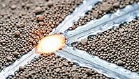 Titanium alloy laser powder bed fusion melt pool at extreme macro scale, showing powder particles, incandescent liquid melt zone and solidified metal tracks simultaneously, additive manufacturing process concept, studio shot, AI generated [IBR125167449]