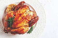 Baked chicken on a white platter with herbs and garlic, on a light background, homemade, no people [IBR125177932]